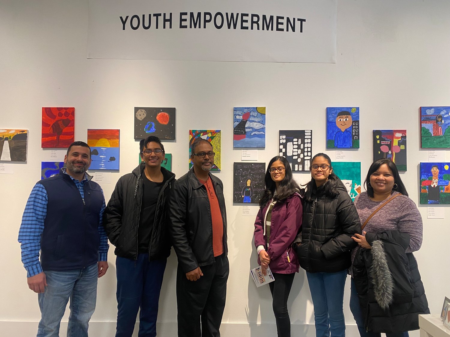 Ashlee Ganesh (third from right) stands with her artwork at the Islip Arts Council Gallery along with her family and Ralph G. Reed Middle School principal Anthony Coggiano (far left).